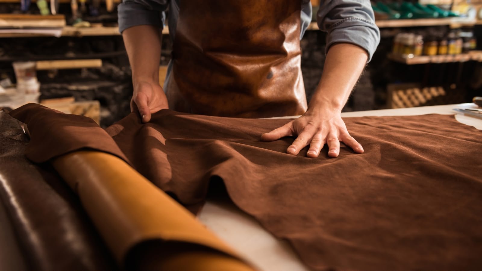 Artisan preparing brown leather in a workshop